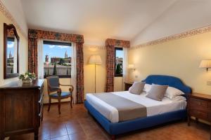 a bedroom with a blue bed and a desk and window at Hotel San Gregorio in Pienza