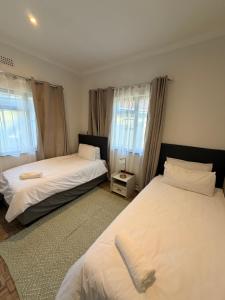 two beds in a room with two windows at Stirling House in Mooiriver