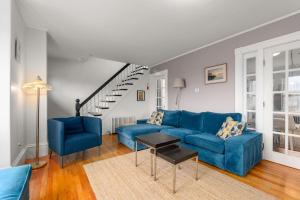a living room with blue couches and a staircase at Helena House in Gloucester