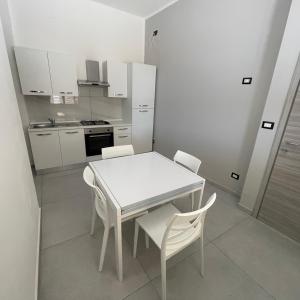 a white kitchen with a white table and chairs at Casa vacanze joppolo in Ioppolo +8 photos