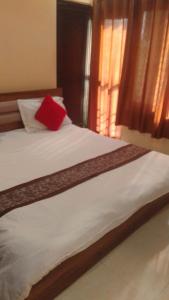 a bed with a red pillow on top of it at guest house honey haldwani in Haldwāni