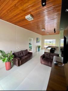a living room with two brown couches and a wooden ceiling at Hotel Vitoria in Matupá