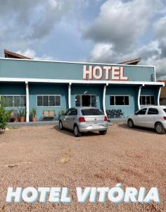 two cars parked in front of a hotel at Hotel Vitoria in Matupá