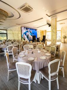 a dining room with tables and chairs and a screen at Riverside Hotel & Restaurant in Acharistsqali