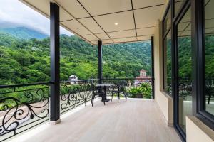 a balcony with a table and chairs and mountains at Riverside Hotel & Restaurant in Acharistsqali