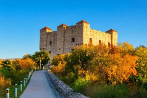 a castle on a hill with a road at Apartman Kadić Senj in Senj