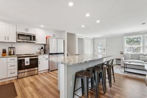 a kitchen with white cabinets and a island with bar stools at Renovated 3BR Near Sandy Point Beach in Annapolis