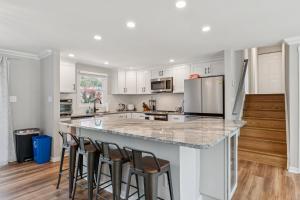 a kitchen with white cabinets and a counter with bar stools at Renovated 3BR Near Sandy Point Beach in Annapolis