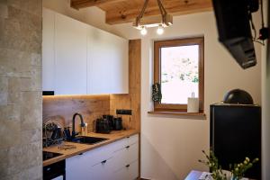 a kitchen with white cabinets and a sink and a window at Nad Drwęcą in Mszano