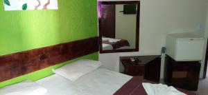 a bedroom with a green wall with a bed and a mirror at Pousada dos Pássaros Pipa in Pipa +10 photos