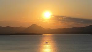 a boat in the water at sunset at Ethaleia Hotel in Moúdhros