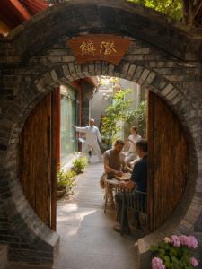 a group of people sitting at a table in an archway at Beijing Templeside Courtyard Hotel 丨 3 metros to the Square丨Free laundry, personalized services large terrace in Beijing