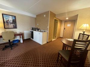 a hotel room with a desk and a table and chairs at Quality Inn & Suites Bay Front in Sault Ste. Marie