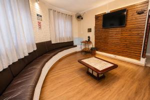 a waiting room with a table and a flat screen tv at Gru Inn Hotel in Guarulhos