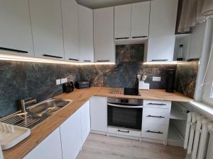 a kitchen with white cabinets and a sink at Diwo Apartament in Koszalin
