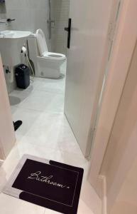 a bathroom with a toilet and a black sign on the floor at أورا ل التأجير اليومي للعائلات فقط in Jeddah +15 photos