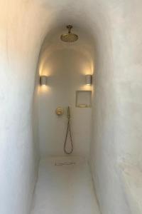 a white corridor with a shower in a white wall at Urano Cave Suites in Santorini