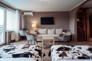 a hotel room with a couch and a table and chairs at Hotel New Wave Wisła in Wisła