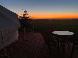 a table and chairs on a deck with a sunset at Thy Glamping in Hurup