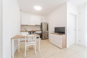 a kitchen with white cabinets and a table and chairs at Martesana47 - 5 Min S Raffaele e Linate Apt in Vimodrone