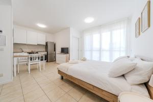 a white bedroom with a large bed and a kitchen at Martesana47 - 5 Min S Raffaele e Linate Apt in Vimodrone