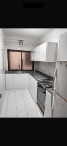 eine Küche mit weißen Schränken und einem Herd mit Backofen in der Unterkunft Private flats in Salalah