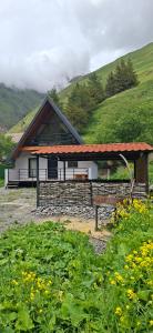 a building with a roof with a field of flowers at kazbegi - Sno Mountain House in Sno