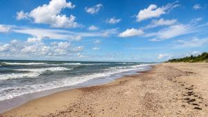 a sandy beach with the ocean on a cloudy day at KOPA CABINS seaside stay in Nida