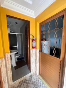 a bathroom with a wooden door and a toilet at Pensão Meg in São José