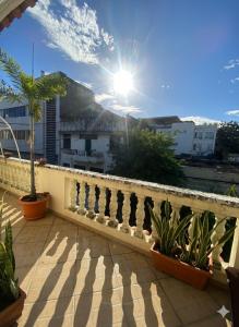 a balcony with a fence and some plants and the sun at La casita de Adri habitación privada en alojamiento compartido en zona colonial in Santo Domingo