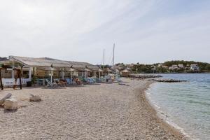 a beach with a group of houses and chairs on it at Lumbarda Resort Apartments in Lumbarda
