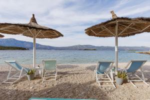 two chairs and two umbrellas on a beach at Lumbarda Resort Apartments in Lumbarda