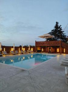 a large swimming pool with chairs and an umbrella at QUEEN appartamenti e camere in Campofilone