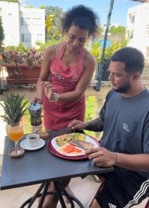 a man and a woman sitting at a table with a plate of food at La casita de Adri habitación privada en alojamiento compartido en zona colonial in Santo Domingo
