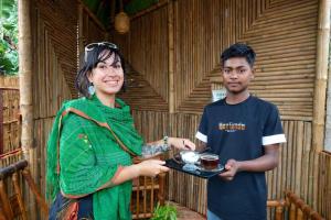 a woman holding a tray of food next to a man at Jolpoddo Retreat in Sreemangal
