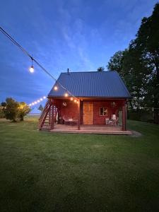 a log cabin with a porch and lights on it at Upeskrastu mājas in Vilcāni +7 photos