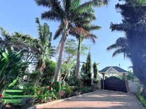 a driveway with palm trees and a gazebo at The Angelique Oasis in Arusha