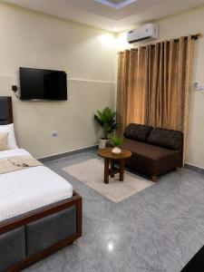 a room with a bed and a couch and a tv at Ecostar apartments in Morogoro