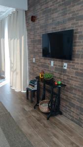 a living room with a table and a tv on a brick wall at Espaço MV Family in Prado