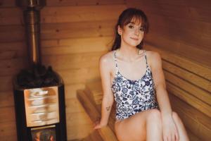 a woman sitting in a sauna next to a stove at Chata Ignasia in Stronie Śląskie +76 photos