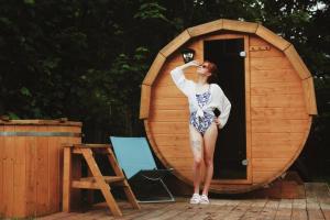 a woman standing in front of a wooden sauna at Chata Ignasia in Stronie Śląskie