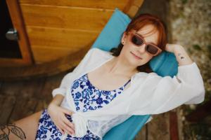 a woman with red hair and sunglasses sitting in a blue chair at Chata Ignasia in Stronie Śląskie