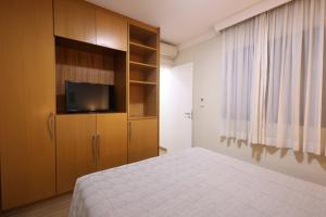a bedroom with a bed and a cabinet with a television at Transamerica Paradise Garden in São Paulo