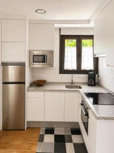 a kitchen with white cabinets and a stainless steel refrigerator at Ca el retriñon in Felechosa