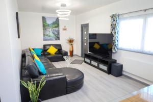 a living room with a black leather couch and a flat screen tv at North Pearl Guesthouse in Porto Moniz