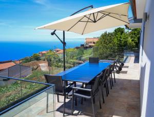 a blue table and chairs on a balcony with an umbrella at North Pearl Guesthouse in Porto Moniz
