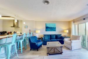 a living room with a blue couch and a kitchen at Dune Our Thing in Kure Beach