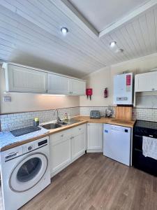 a kitchen with a washing machine and a sink at The Castle Front Nest in Inverness