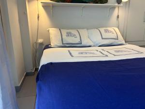 a bed with blue and white sheets and pillows at Royal Zea Suite 3 in Piraeus +2 photos