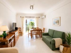 a living room with a green couch and a dining room at Apartamento Oásis Parque 3 in Portimão